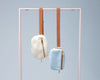Cream sherpa and light blue denim belt bags hanging from a pink rack with brown straps and gold zippers.