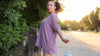 Woman wearing a mauve oversized T-shirt and matching shorts outdoors at sunset.