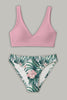 Flat lay of a pink V-neck bikini top and tropical-print bottoms with green leaves and pale pink flowers.