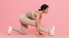 Woman in blush activewear stretching in a low lunge against a pink background