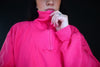 Close-up of a bright pink half-zip pullover with a high collar and relaxed sleeves.