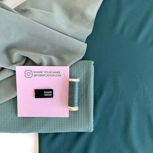 Sage green athletic knit mesh fabric with matching thread, folded fabric, and a Fabric + Flow card.