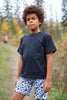 Child wearing a navy cotton jersey T-shirt and patterned shorts outdoors.