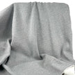 A close-up of draped heather gray fabric with soft folds and a visible white inner lining or backing at the bottom right.