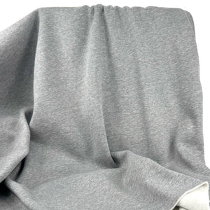A close-up of draped heather gray fabric with soft folds and a visible white inner lining or backing at the bottom right.