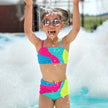 Child in a colorful swimsuit playing in water with water splashes around.